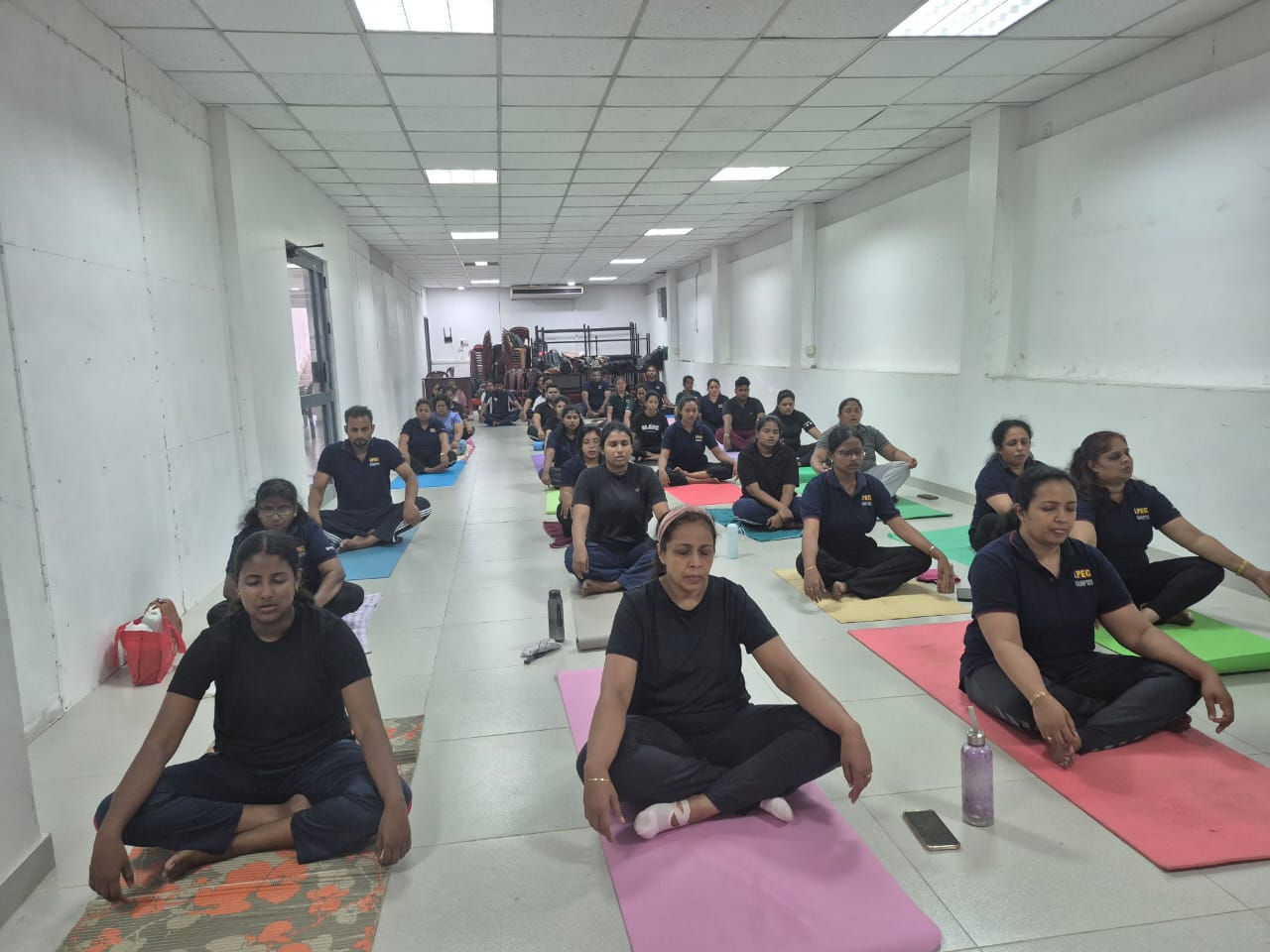 Corporate yoga class seated on mats in navy uniforms