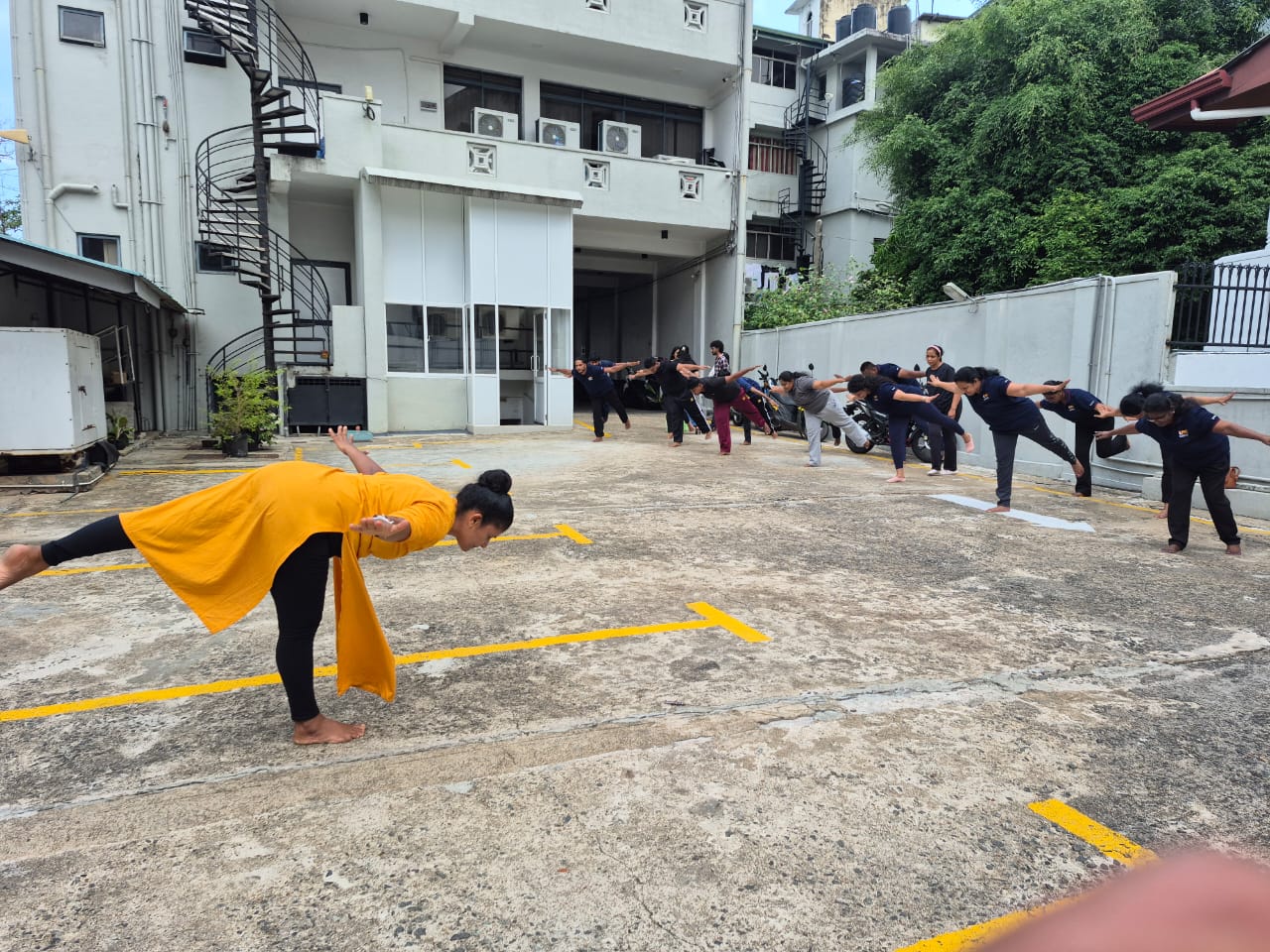Kumari leading an outdoor workplace class in a warrior variation