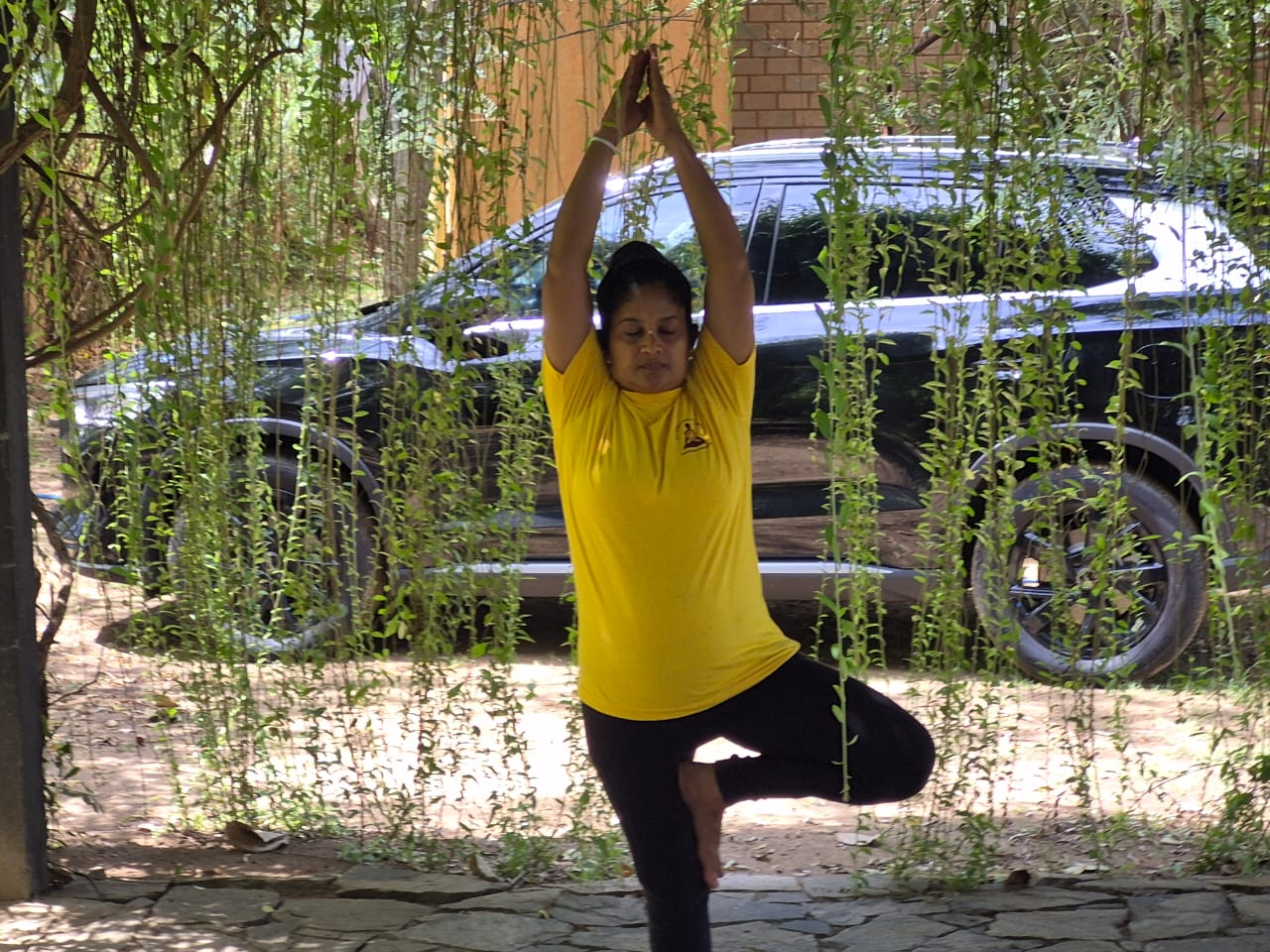 Kumari Wahalathanthri in tree pose, wearing an Ashtanga Yoga Lanka shirt